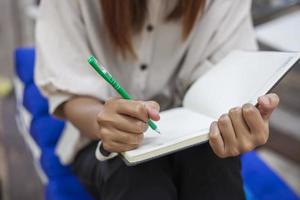 The girl's hand holding a pen is writing down something on a notebook. photo