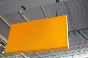 An orange and yellow shop name hanging sign mounted on the ceiling. photo