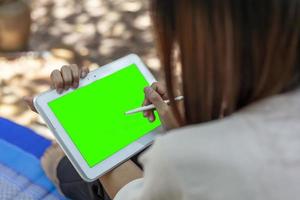 Woman's hand holding tablet and pen taking note of something with green space for text or online media. photo