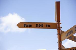 Signs giving directions to different cities against a clear sky background. photo