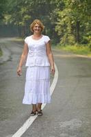 middle age woman walk on white line on road outdoor photo