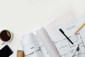 Creative flat lay of architects white table with roll blueprints, architectural project plan, engineering tools, office supplies and a cup of hot coffee,Workspace for designer concept photo