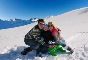 family having fun on fresh snow at winter vacation photo