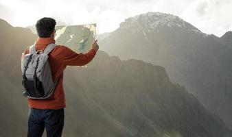 A young traveler man on the top of mountain with backpack and look searching direction on location map, Adventure and travel in the concept, Travelling tour in Asia Leh Ladakh,india photo