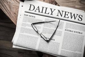 periódico con el titular de las noticias con gafas sobre una mesa de madera, concepto de maqueta de periódico diario foto