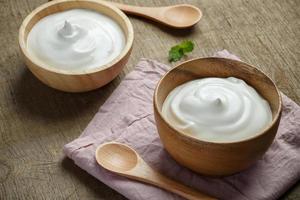 yogur griego en un cuenco de madera con cucharas sobre fondo de madera foto