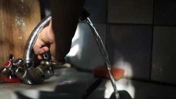 Water flows from tap. Water jet from pipe. Tap water in sink. Water flows in light of sun. Kitchen details in light from window. video