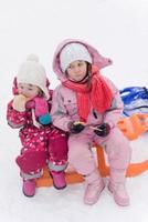 portrait of two little grils sitting together on sledges photo