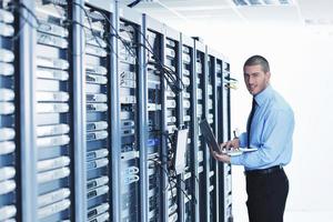 businessman with laptop in network server room photo