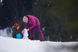 familia feliz construyendo muñeco de nieve foto