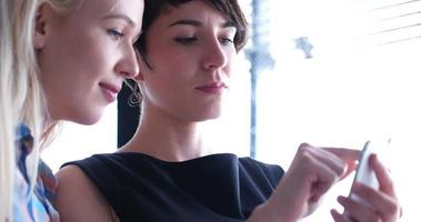 two attractive business women with a cell phone discuss business photo