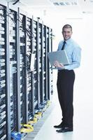 businessman with laptop in network server room photo