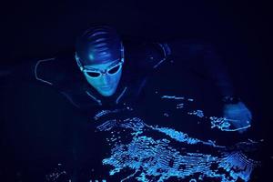 authentic triathlete swimmer having a break during hard training on night neon gel light photo