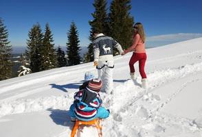 familia divirtiéndose en la nieve fresca en las vacaciones de invierno foto