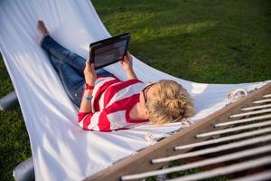 woman using a tablet computer while relaxing on hammock photo