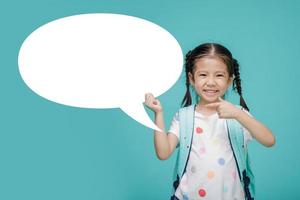 Excited young Asian little girl with empty speech bubble, empty space in studio shot isolated on colorful blue background, Educational concept for school photo