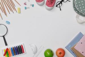 flatlay creativo de educación mesa blanca con mochila, libros para estudiantes, zapatos, crayón colorido, anteojos, espacio vacío aislado en fondo blanco, concepto de educación y regreso a la escuela foto