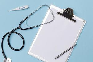 Creative flatlay of doctor medical equipment blue table with stethoscope, medical documents, thermometer, syringe and pills, Health care concept, Top view with copy space, Isolated on blue photo