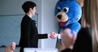 boss dresed as bear having fun with business people in trendy office photo