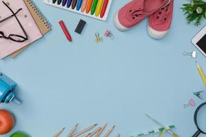 Creative flatlay of education blue table with student books, shoes, colorful crayon, eye glasses, empty space isolated on blue background, Concept of education and back to school photo