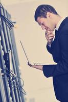 businessman with laptop in network server room photo