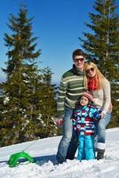 familia divirtiéndose en la nieve fresca en invierno foto