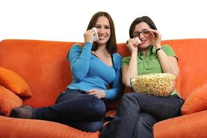 female friends eating popcorn and watching tv at home photo