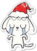 cute distressed sticker cartoon of a dog crying wearing santa hat vector