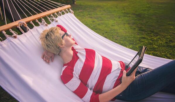 woman using a tablet computer while relaxing on hammock photo