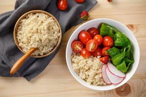 Quinoa salad with vegetables, raspberry and tomatoes on the wooden table. Super food for healthy and concept of balanced diet photo