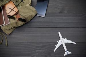 Traveler's accessories with passport, books of travel plan, wallet, camera, backpack and airplane toy on black wooden table, Flat lay with copy space, Travel concept background photo