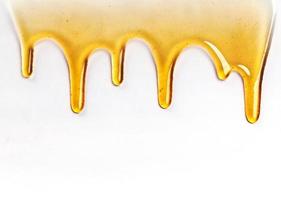 Dripping golden sweet honey flowing down the frame from the top over white with copyspace and text photo