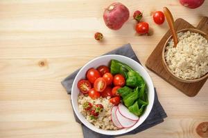 Quinoa salad with vegetables, raspberry and tomatoes on the wooden table. Super food for healthy and concept of balanced diet photo