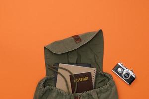 Top view mockup of Traveler's accessories with passport, books of travel plan, camera and backpack isolated orange background with empty space,Tropical travel concept photo