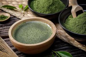 polvo de té verde matcha orgánico japonés en tazón con batidor de alambre y hoja de té verde sobre fondo de madera, producto orgánico de la naturaleza para la salud con estilo tradicional foto