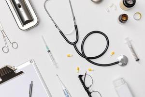 Creative flatlay of doctor medical equipment white table with stethoscope, medical documents, thermometer, syringe and pills, Health care concept, Top view with copy space, Isolated on white photo