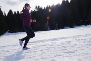 joven mujer trotar al aire libre en la nieve en el bosque foto