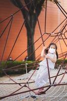 Portrait child 5-6 years old. Happy children are playing on red rope net at outdoor playground. Kid enjoy physical activity and improve her balance skills and strengthen muscles. Vertical image. photo