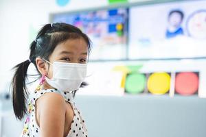 Portrait image child 5-6 years old. Cute girl wearing white face mask while learning about traffic lights before taking test ride on bicycle on mock road. Kid are excited and happy to learn new things photo