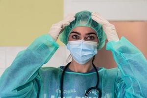 The female animal surgeon or veterinarian puts on a medical face mask. Doctor is preparing for surgery in the operation room. Medicine and healthcare photo