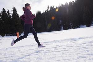 joven mujer trotar al aire libre en la nieve en el bosque foto