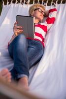 woman using a tablet computer while relaxing on hammock photo