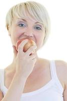 una joven feliz come manzana verde aislada en blanco foto