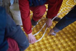 workers installing underfloor heating system photo