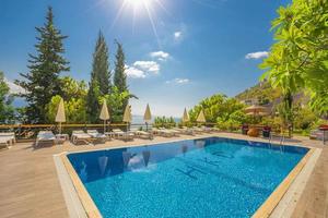 lujosa piscina en el jardín de una villa privada, silla colgante con almohadas para turistas de ocio, en verano foto