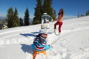 familia divirtiéndose en la nieve fresca en invierno foto