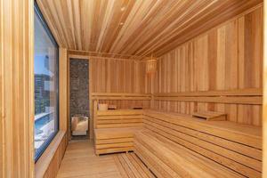 Interior of Finnish sauna, classic wooden sauna with hot steam. Russian bathroom. Relax in hot sauna with steam. Wooden interior baths, wooden benches and loungers accessories for sauna, spa complex. photo