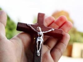 Wooden cross bead necklace holding in hands, natural blurr bokeh background, soft and selective focus. photo