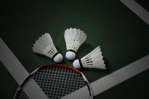 Cream white badminton shuttlecocks and rackets on green floor in indoor badminton court photo