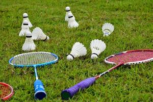 Badminton outdoors equipments white and yellow plastic shuttlecocks and badminton rackets, on grasslawn, soft and selective focus on shuttlecocks outdoor badminton playing concept photo